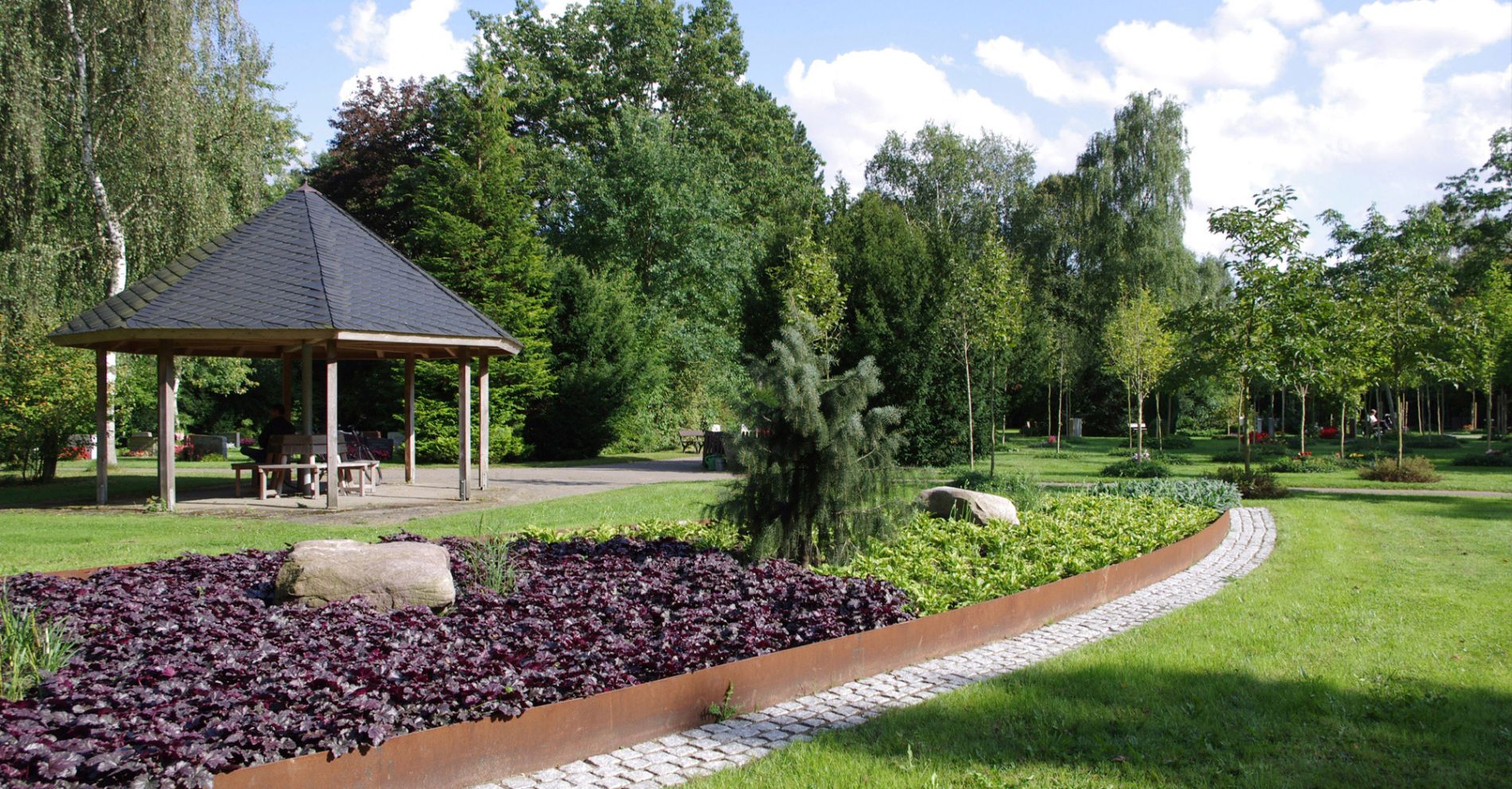 Pavillon und gepflegtes Staudenbeet in der parkähnlichen Landschaft